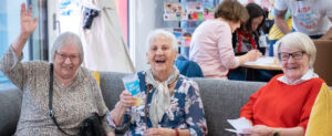 Drei gutgelaunte ältere Damen auf einem Sofa sitzend