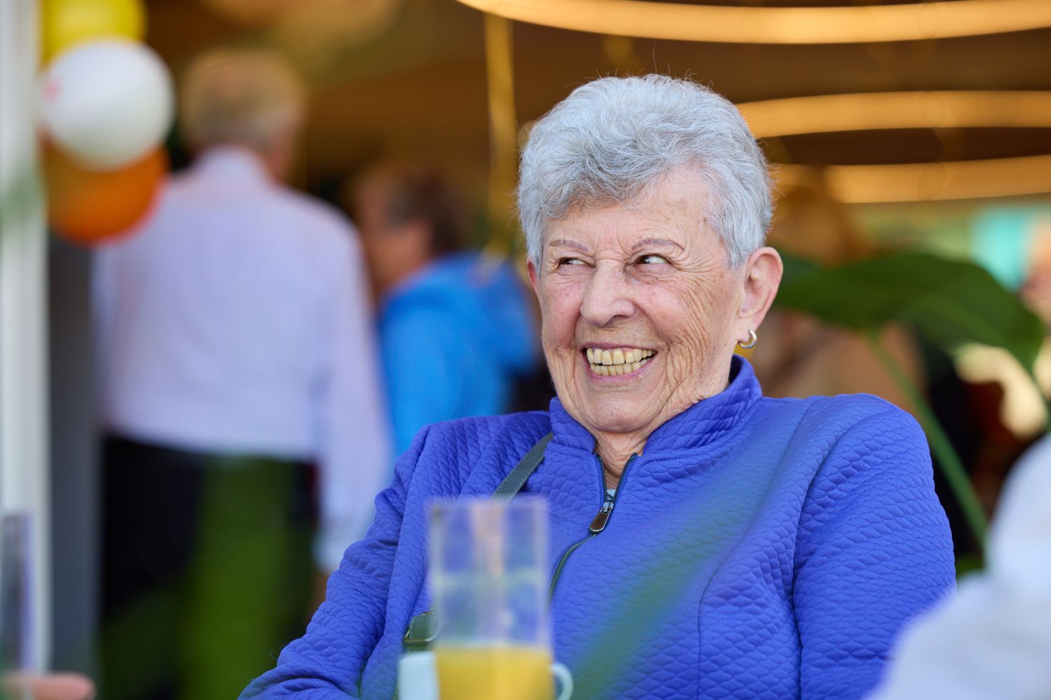 Seniorin in blauem Pullover lacht.