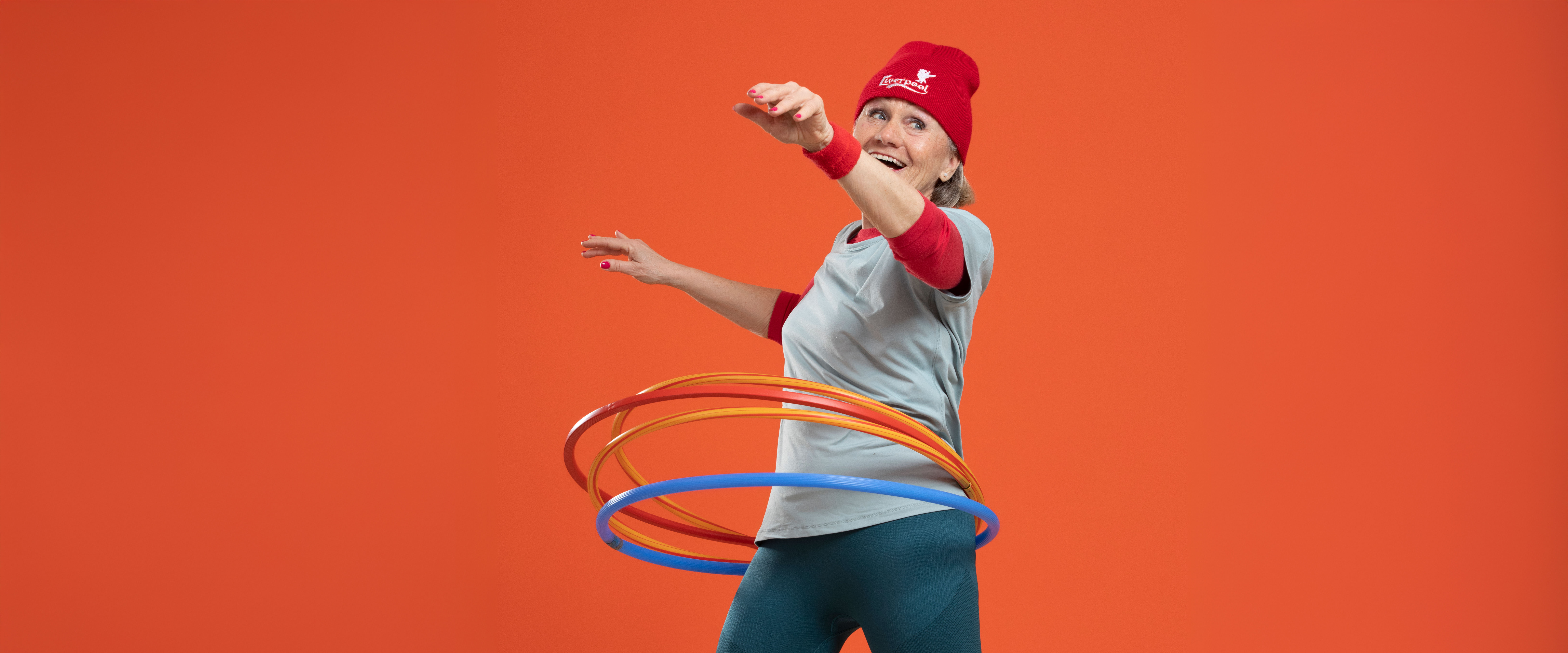 ChatGPT: Eine fröhliche ältere Dame mit sportlicher Kleidung tanzt mit mehreren bunten Hula-Hoop-Reifen.