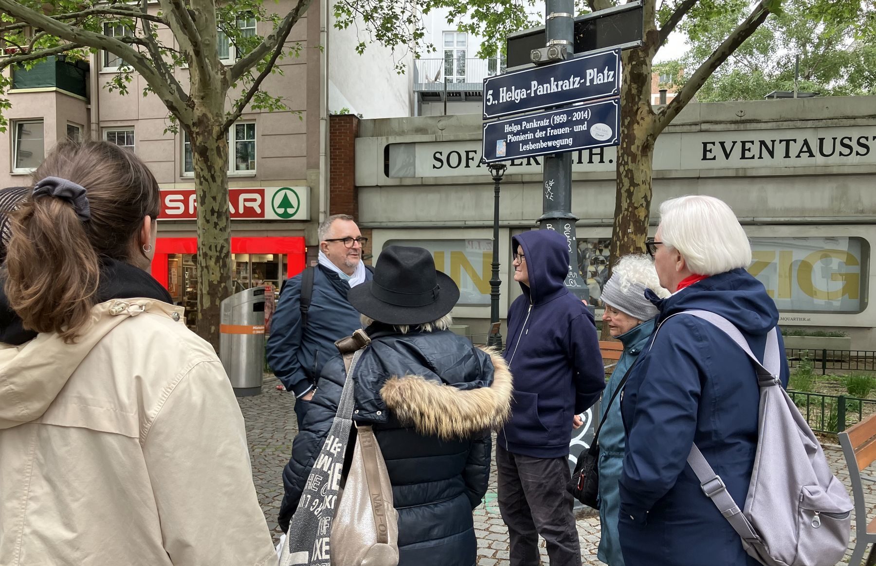Eine Gruppe von Personen steht während eines Stadtspaziergangs in Wien-Margareten vor einem Straßenschild.