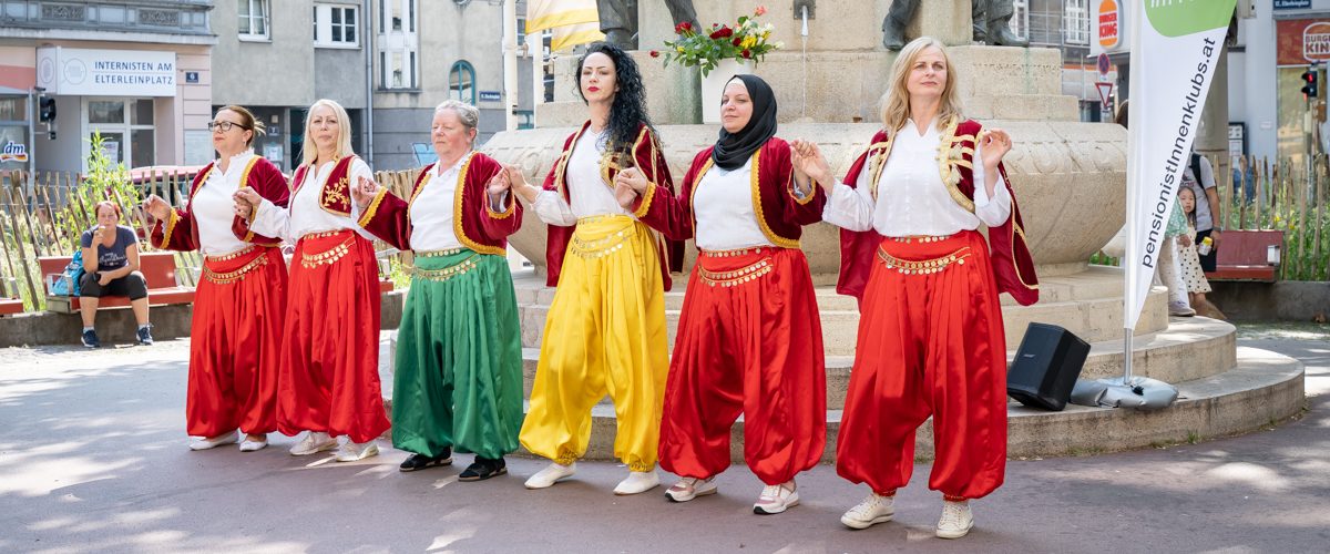 Frauen in bosnischer Tracht tanzen gemeinsam.