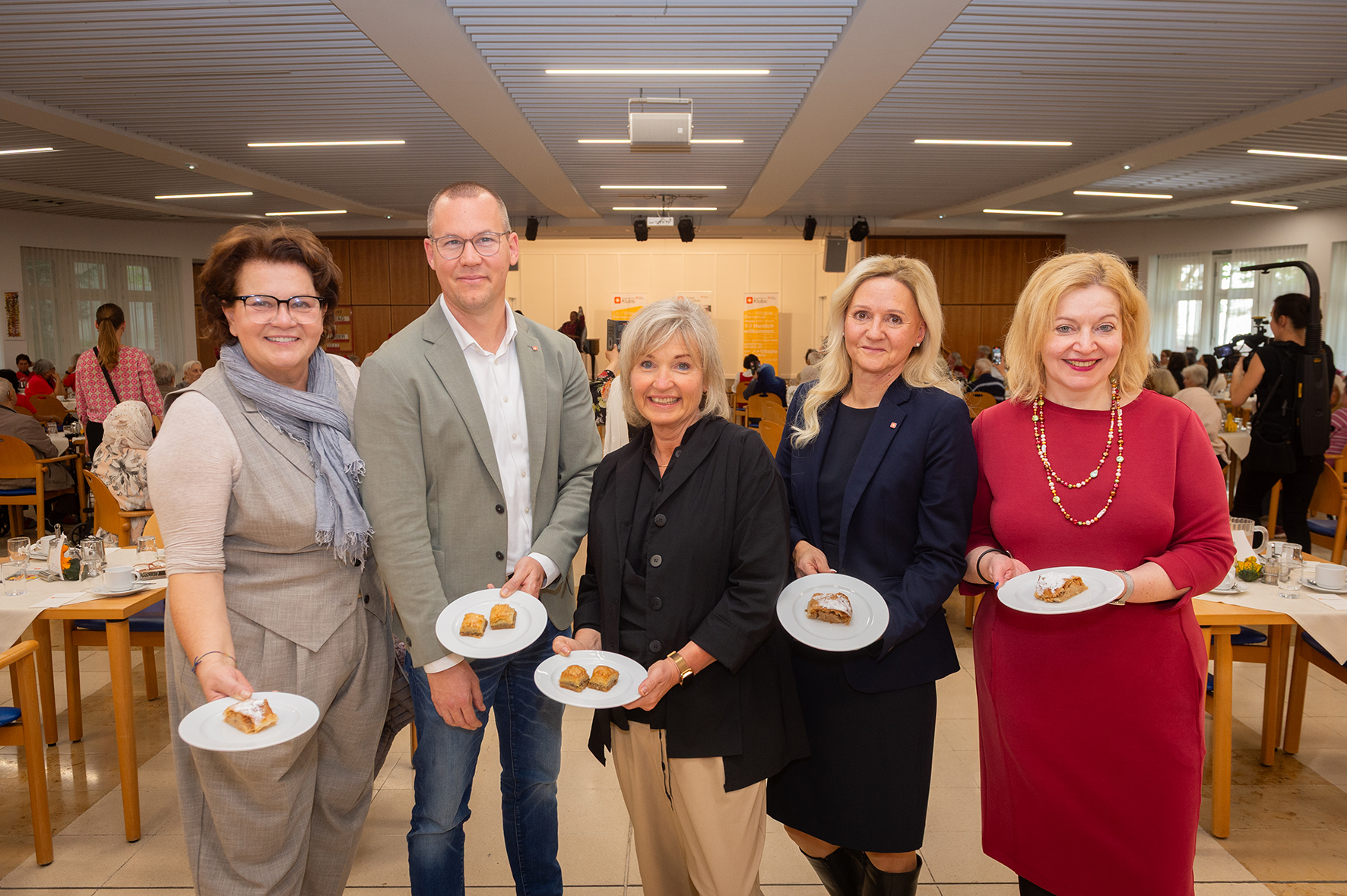 Vertreter*innen der Geschäftsleitung der Häuser zum leben und politische Ehrengäste halten Teller mit Baklava in die Kamera.