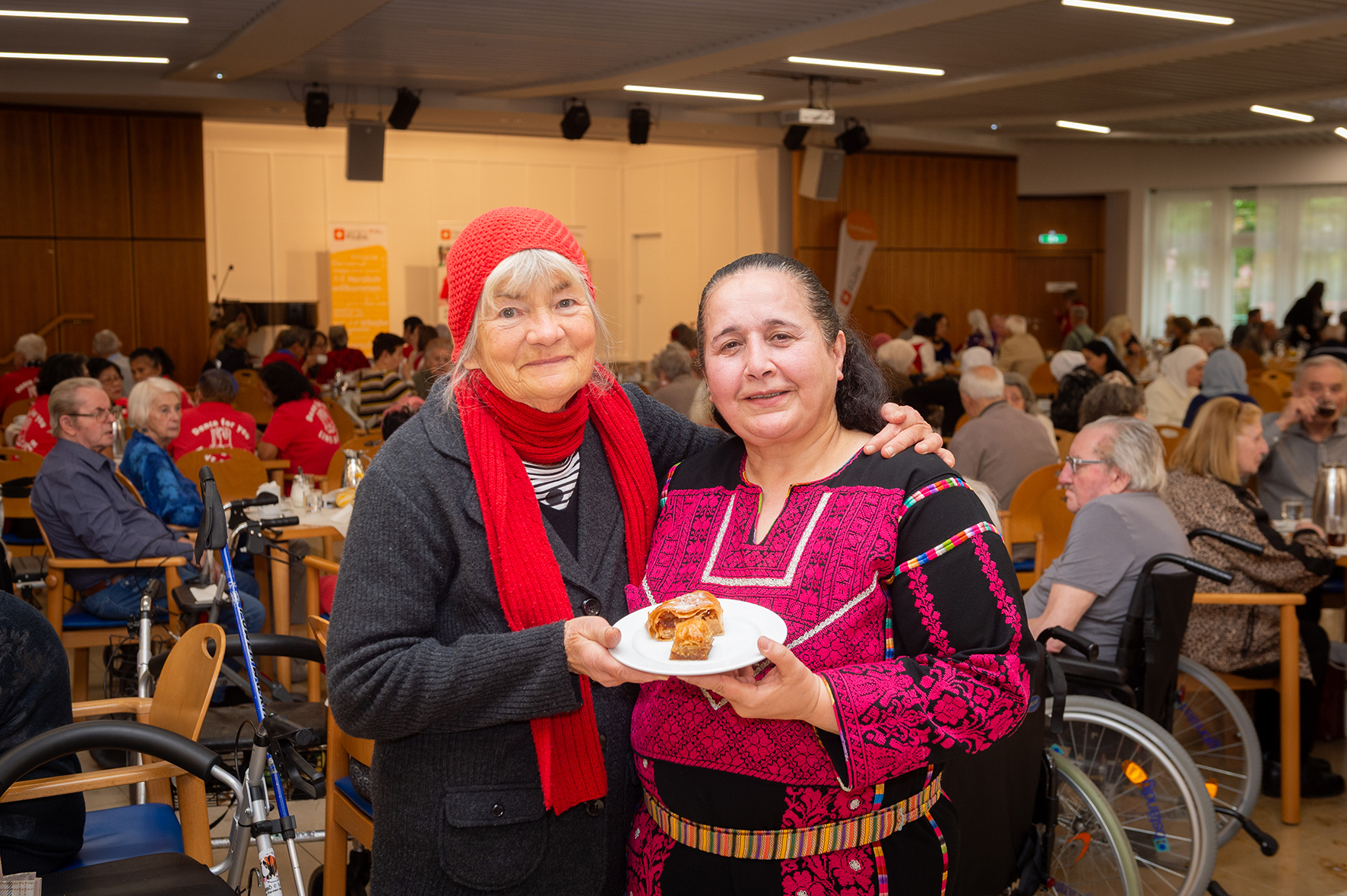 Zwei Senior*innen halten einen Teller mit Baklava.