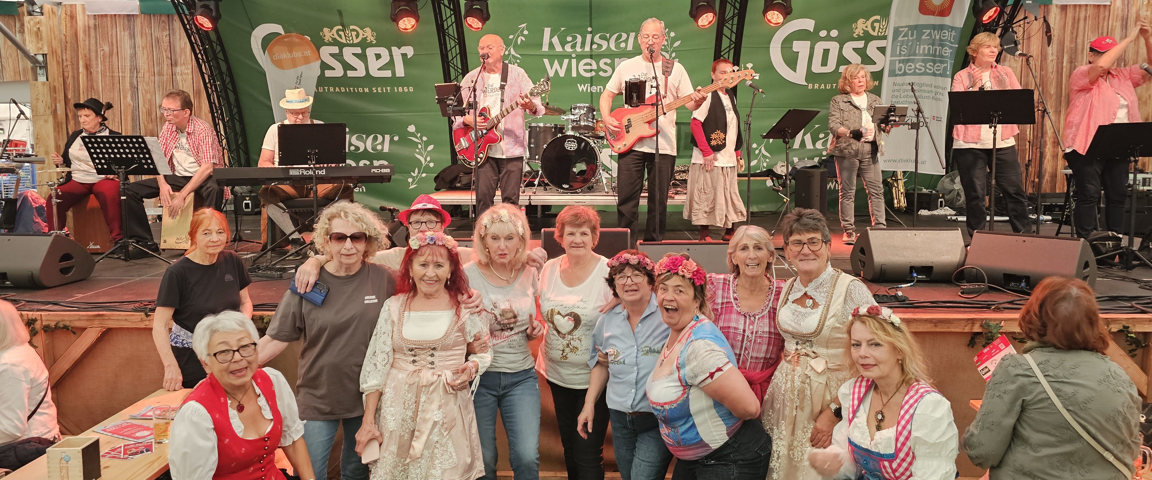 Eine Gruppe Senior*innen posiert vor der Bühne, auf der gerade die Werder Klub Band auftritt.