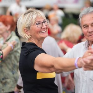 Ein älteres Paar tanzt und lächelt dabei in die Kamera.