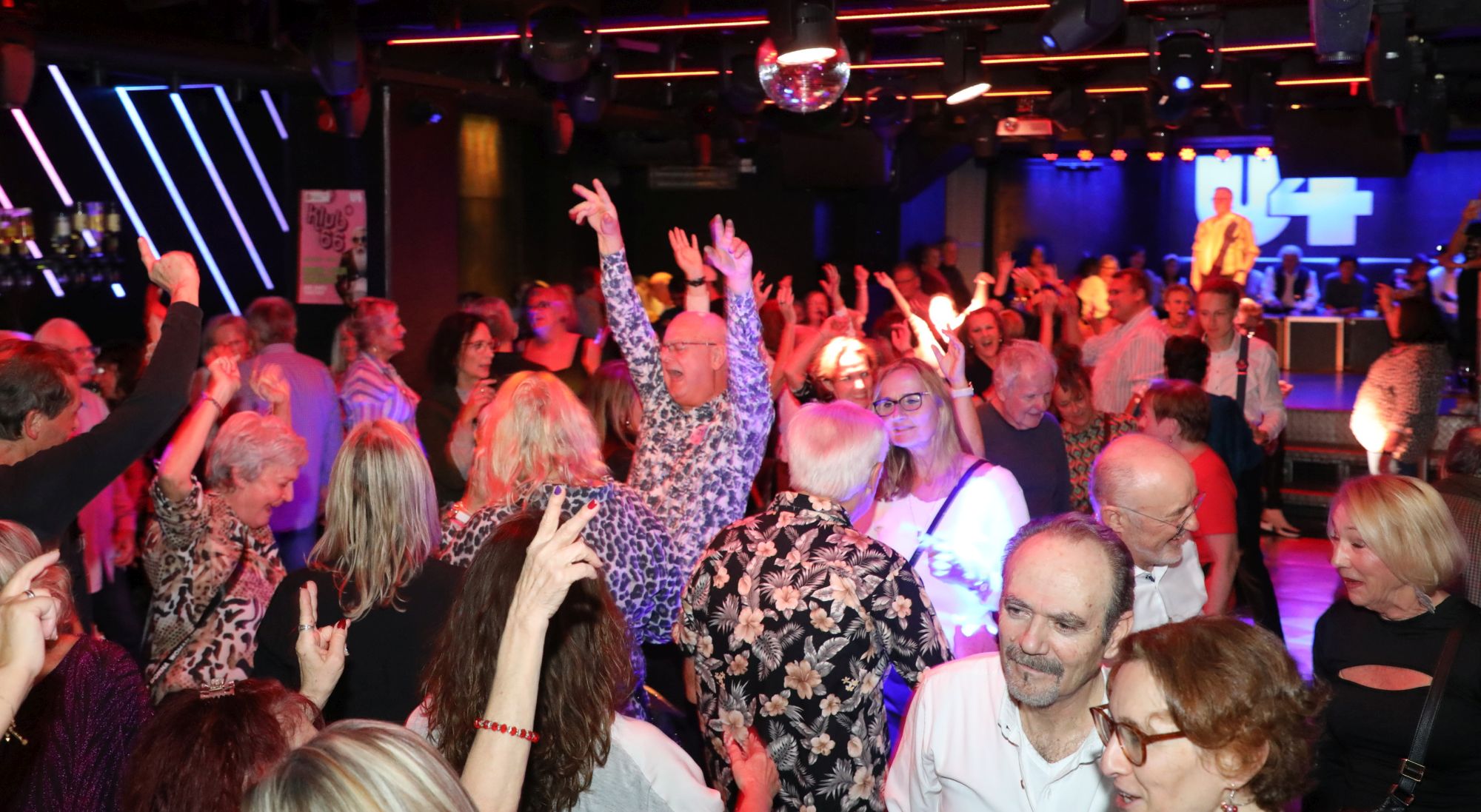 66er Klub im U4 am 06.11.2025 - © Conny de Beauclair man sieht die Menge im U4, ein Mann sticht heraus, da er seine Arme in die Höhe schmeißt und offensichtlich lauthals singt beziehungsweise schreit.