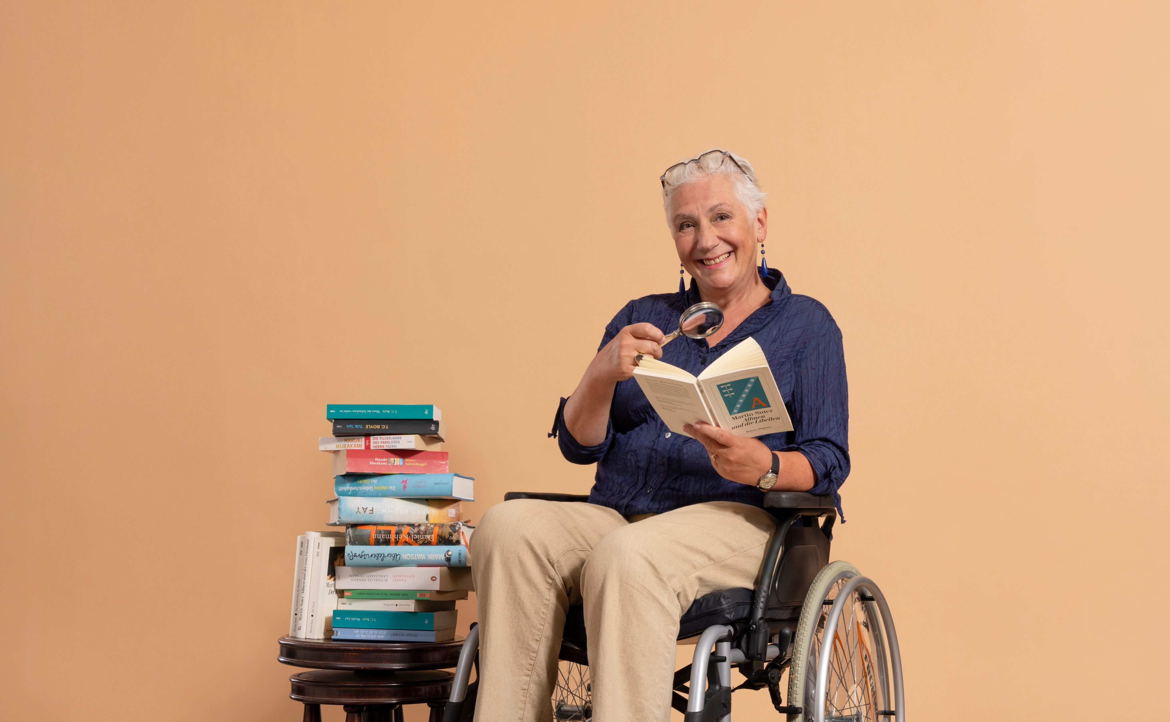 Frau in Rollstuhl hält Buch in der Hand