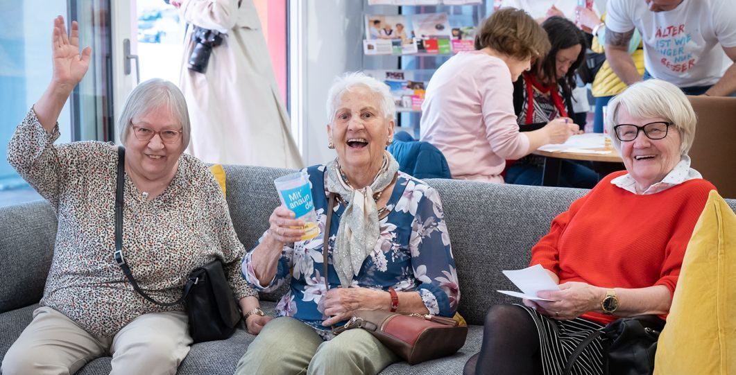 Drei Seniorinnen sitzen auf einem Sofa.