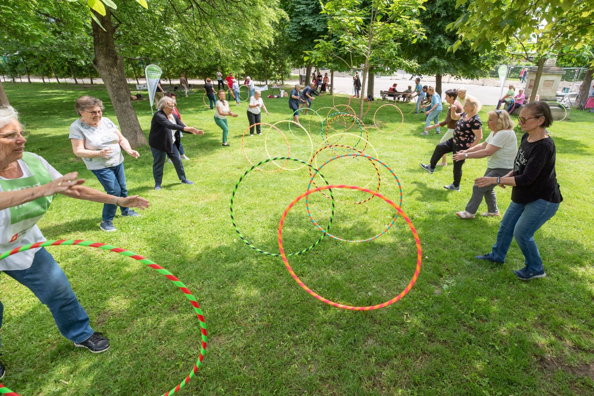 Frauen rollen sich in einem Park Hula-Hoop-Reifen zu.