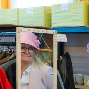 Eine Frau mit Hut sieht sich in den Spiegel.