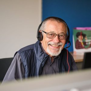 Ein Pensionist mit Kopfhörern an der Telefon-Hotline der Pensionist*innenklubs.
