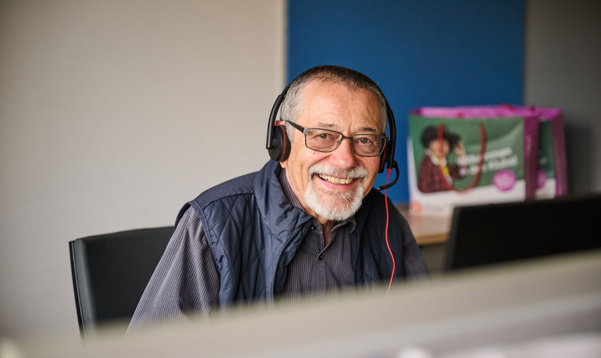 Ein Pensionist mit Kopfhörern an der Telefon-Hotline der Pensionist*innenklubs.
