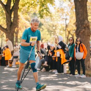 Ein älterer Mann geht beim Nordic Walking Day 2026 im Wiener Prater, im Hintergrund Zuschauer*innen.