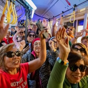 Mehrere Menschen lachen und halten die Hände in die Höhe in der Disco-Straßenbahn der Pensionist*innenklubs.
