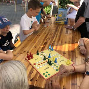 Kinder und Senior*innen spielen an einem Tisch Mensch ärgere dich nicht.