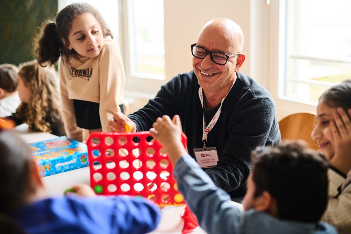 Ein Mann spielt mit Kindern "Vier gewinnt"