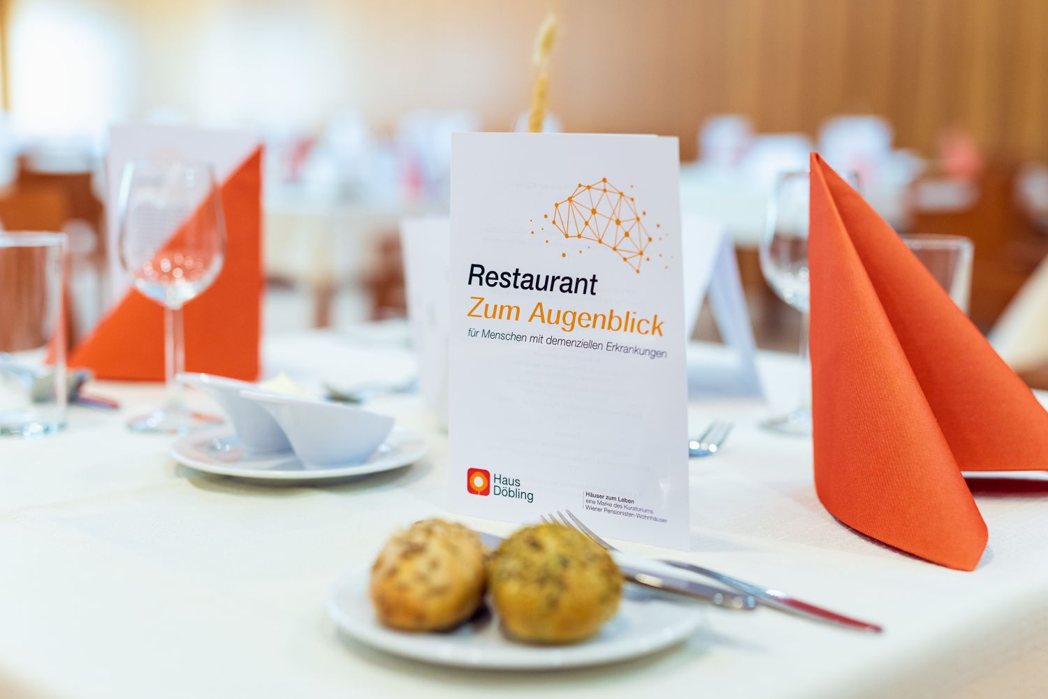 Zwei Knödel auf einem Teller auf einen schön angerichteten Tisch mit einer Menükarte mit der Aufschrift "Restaurant Zum Augenblick"