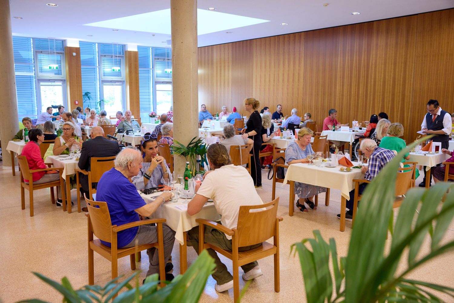 Mehrere Menschen sitzen an Tischen im Demenz-Restaurant.