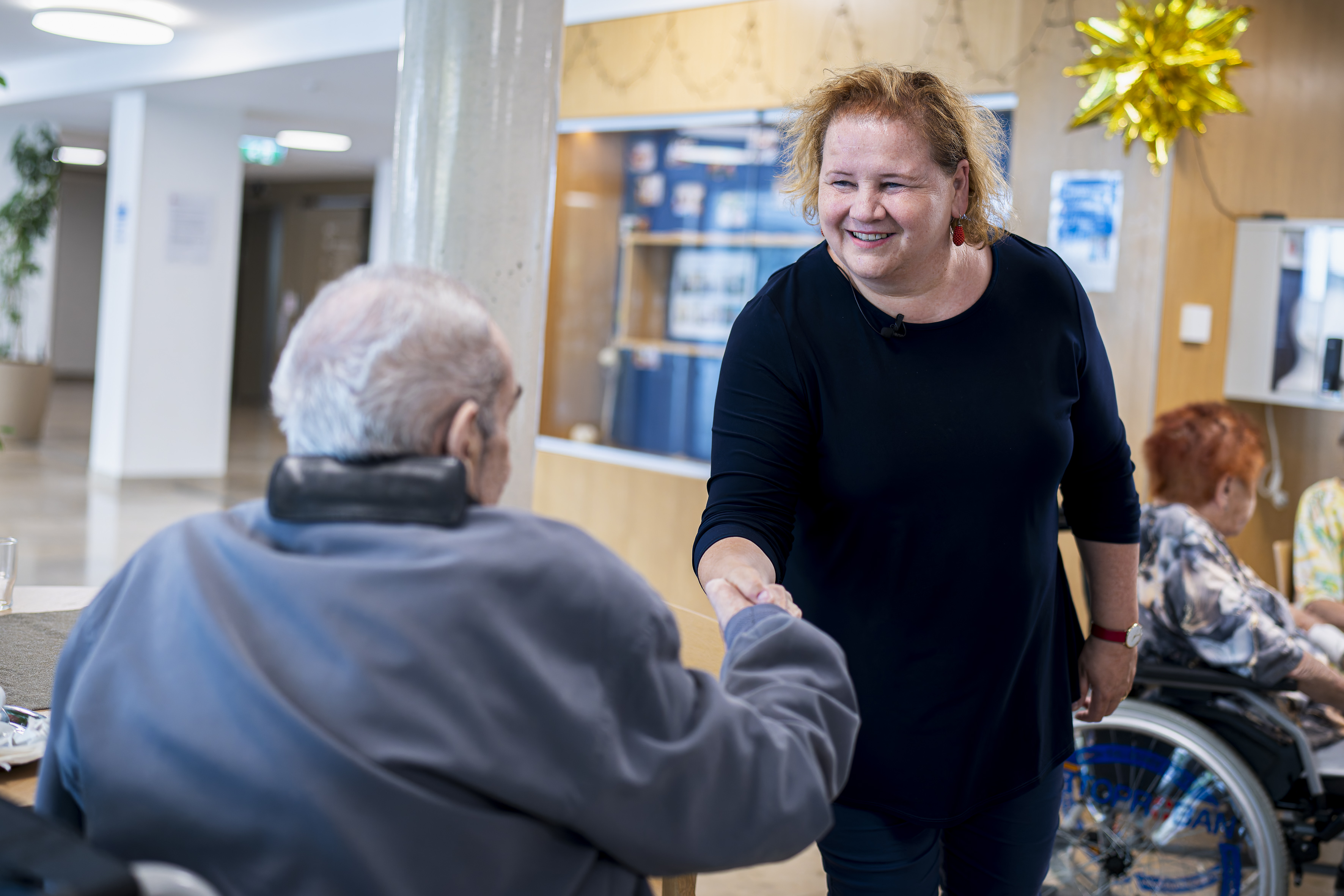 Bundesministerin Korinna Schumann begrüßt einen Bewohner im Haus Penzing.