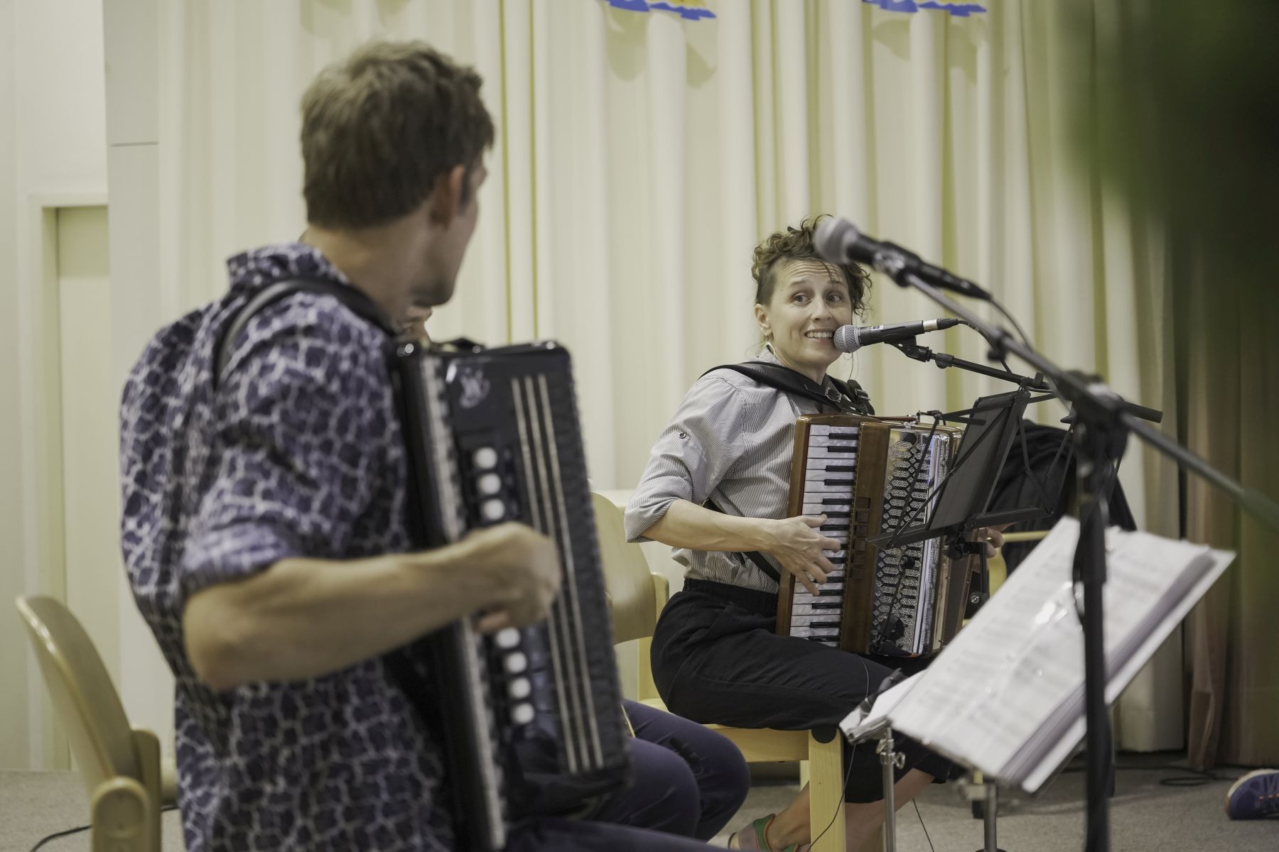 Ein Musiker und eine Musikerin mit Akkordeon sitzen auf der Bühne während eines Konzerts im Rahmen von Kultursommer Wien im Pensionisten-Wohnhaus Rossau in Wien-Alsergrund.