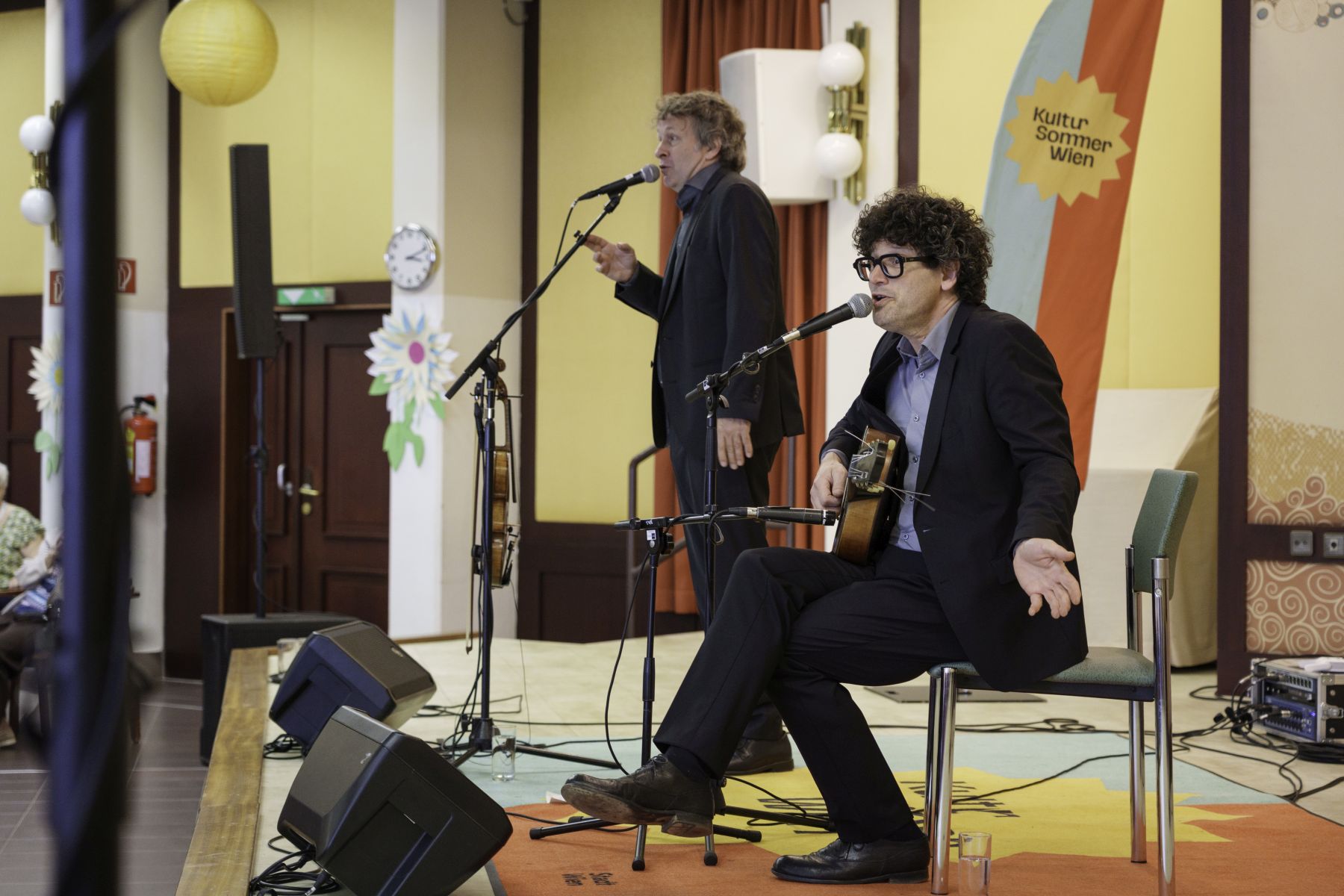 Die Band "Die Strottern" bestehend aus zwei Männern auf der Bühne bei einem Konzert im Rahmen von Kultursommer Wien im Pensionisten-Wohnhaus Gustav Klimt in Wien-Penzing.
