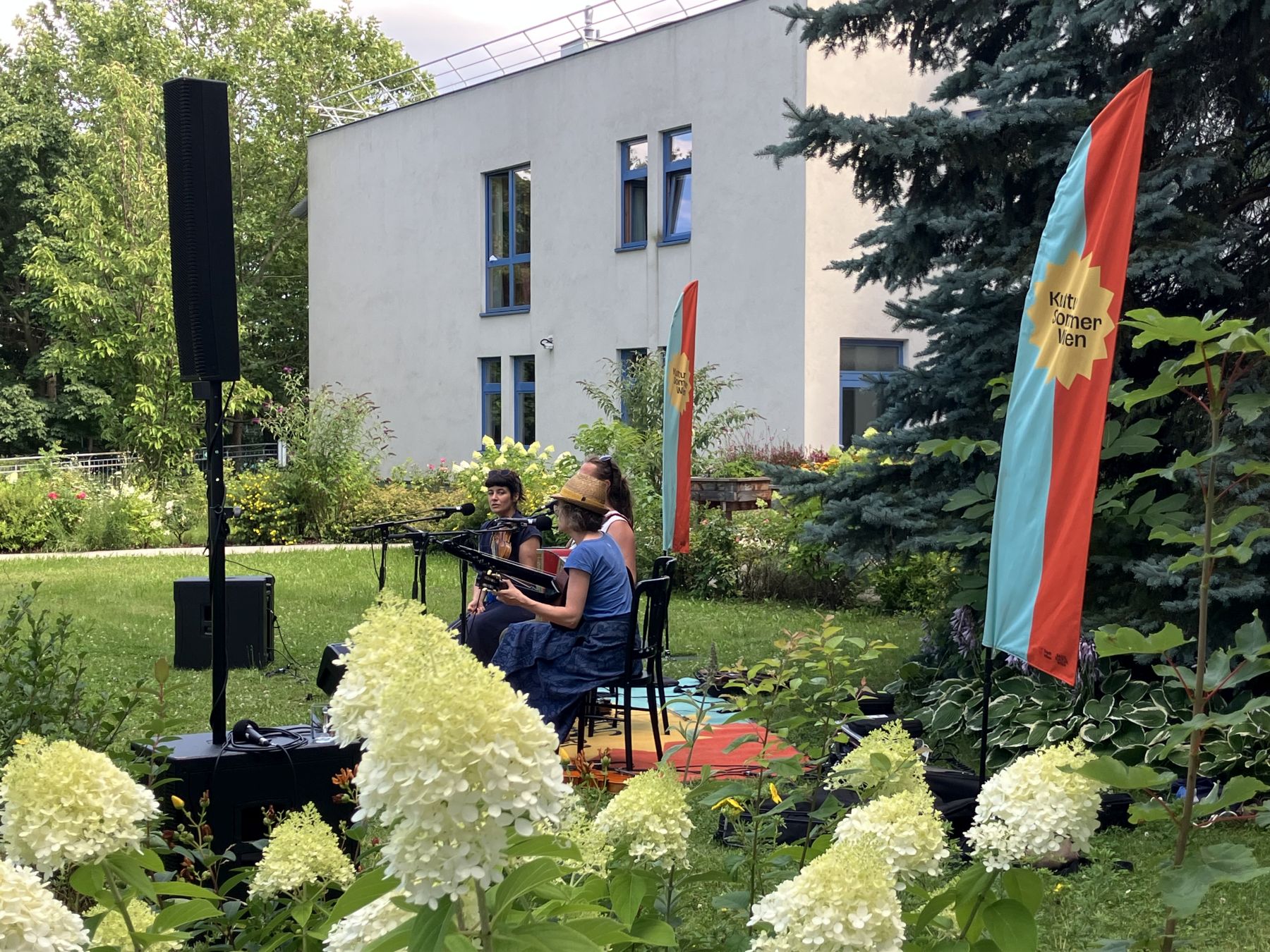 Zwei Musikerinnen und ein Musiker beim Gartenkonzert im Garten des Pensionisten-Wohnhauses Föhrenhof in Wien.
