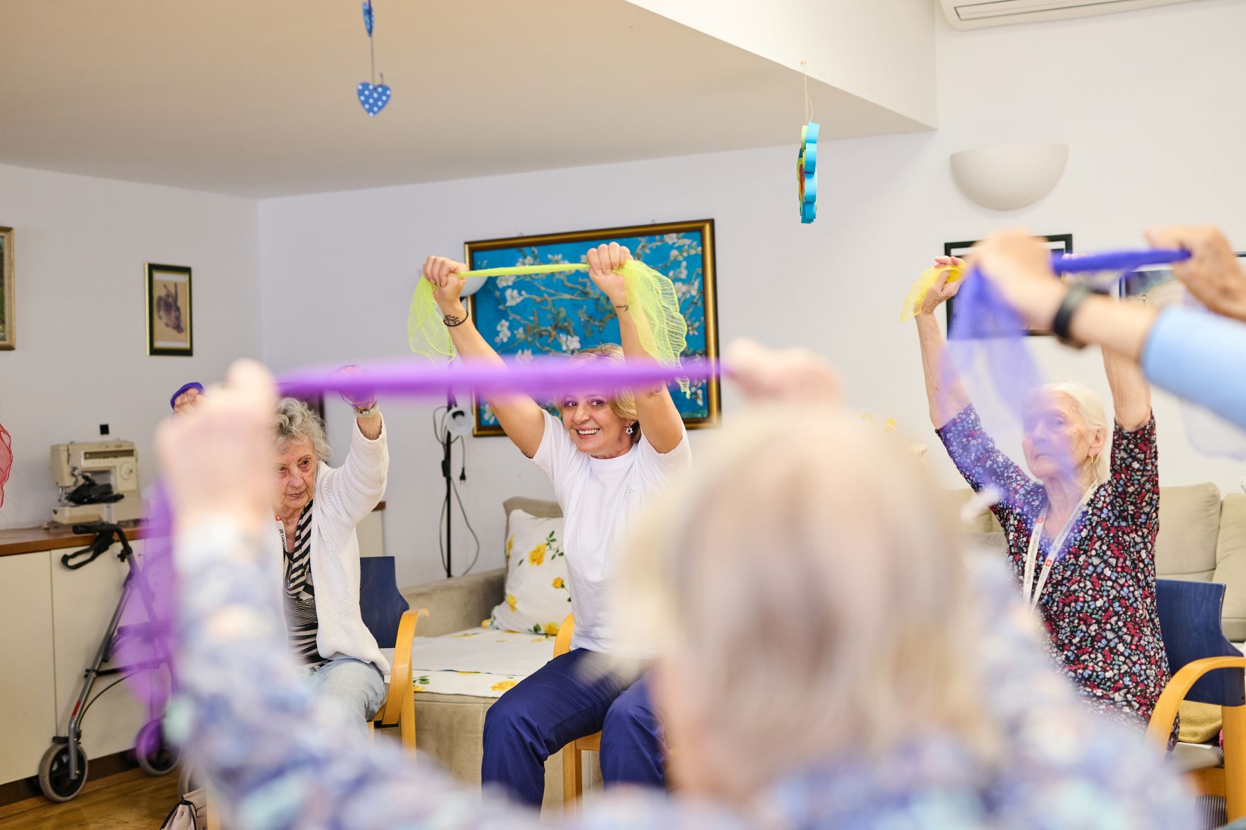 Senioren und Seniorinnen üben mit einem Gymnastikband im Haus Am Mühlengrund.
