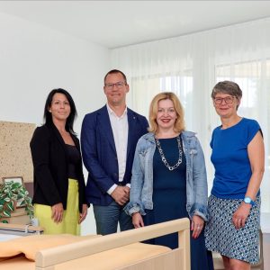 Jasmin Tomassi, Direktorin Haus An der Türkenschanze, Simon Bluma, stellvertretender Geschäftsführer Häuser zum Leben, Anita Bauer, Geschäftsführerin Fonds Soziales Wien (FSW) und Silvia Nossek, Bezirksvorsteherin Wien-Währing stehen hinter einem Bett in einer neuen Pflegestation im Haus An der Türkenschanze.