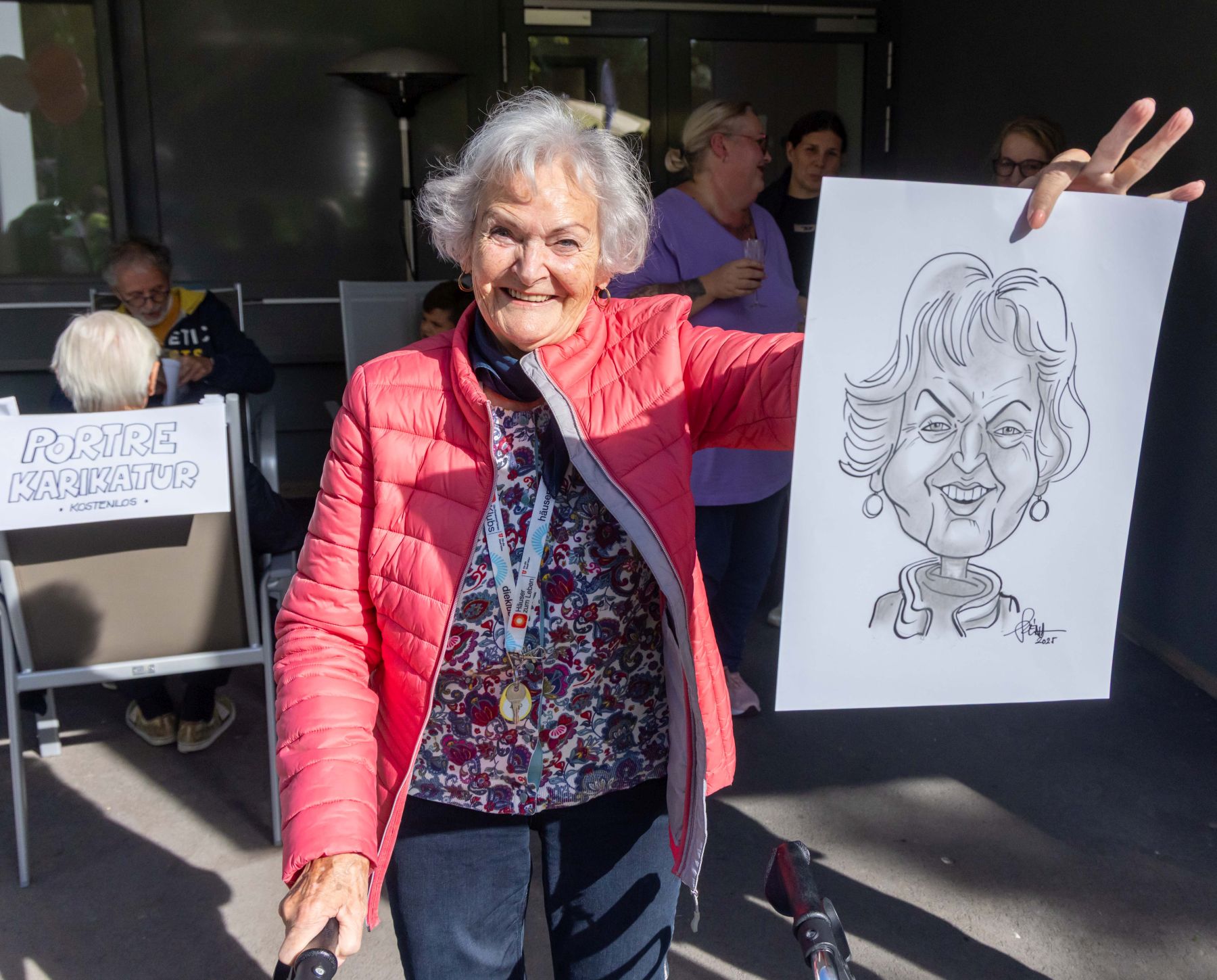 Eine Seniorin hält eine von ihr gezeichnete Karikatur in der Hand.