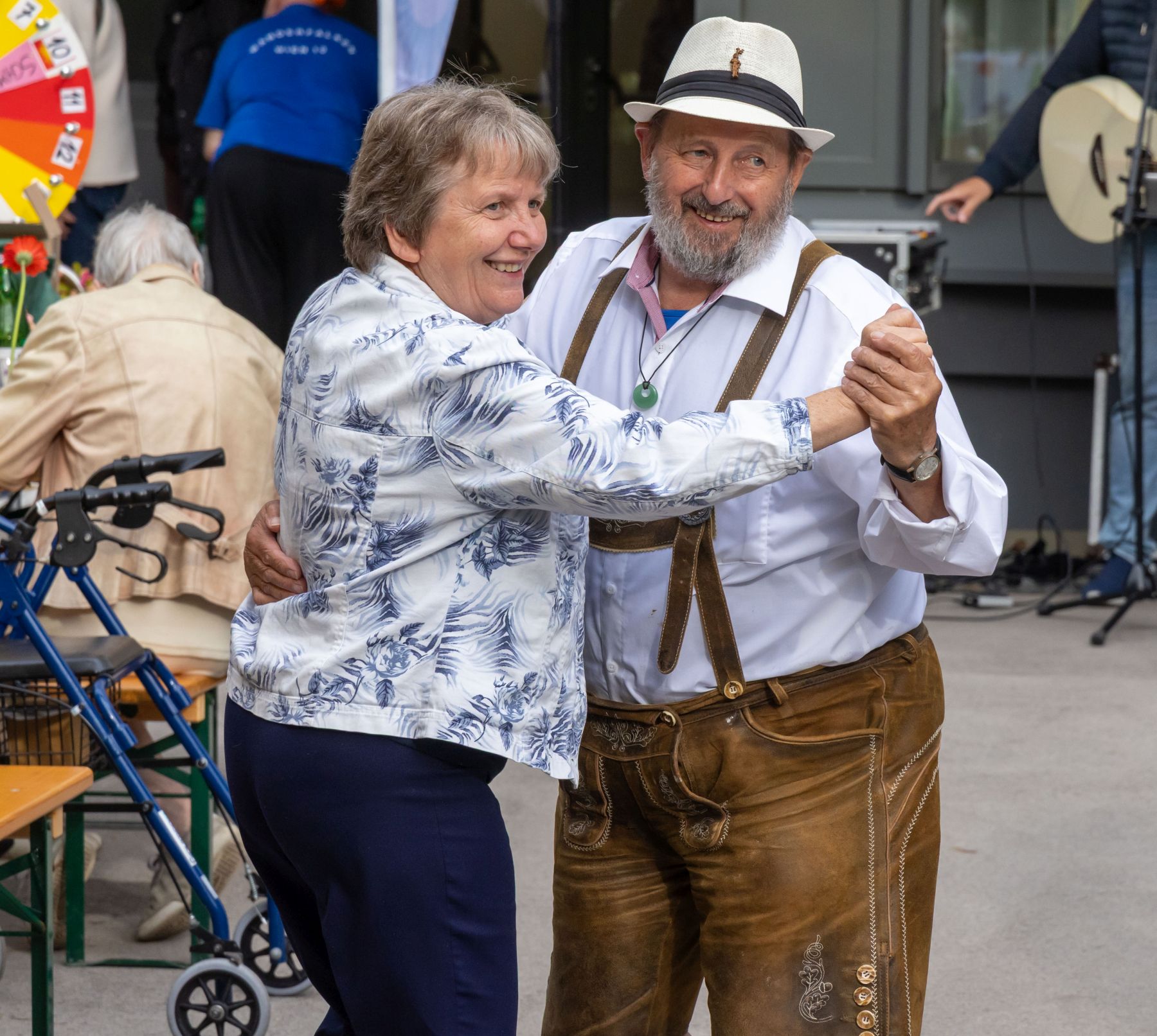 Eine Frau und ein Mann mit Hut und Lederhose tanzen.
