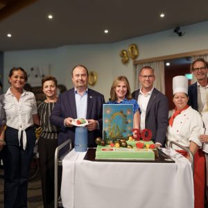 Mehrere Personen, u.a. Alexander Nikolai, Bezirksvorsteher Wien-Leopoldstadt, Simon Bluma, stellvertretender Geschäftsführer Häuser zum Leben und Claudio May, Direktor Haus Prater, stehen hinter einer grünen Torte mit der Aufschrift "Haus Prater - 30"
