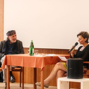 Ein Mann und eine Frau sitzen auf einer Bühne und sprechen.