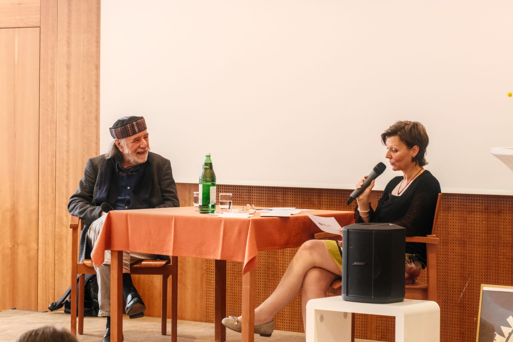Ein Mann und eine Frau sitzen auf einer Bühne und sprechen.