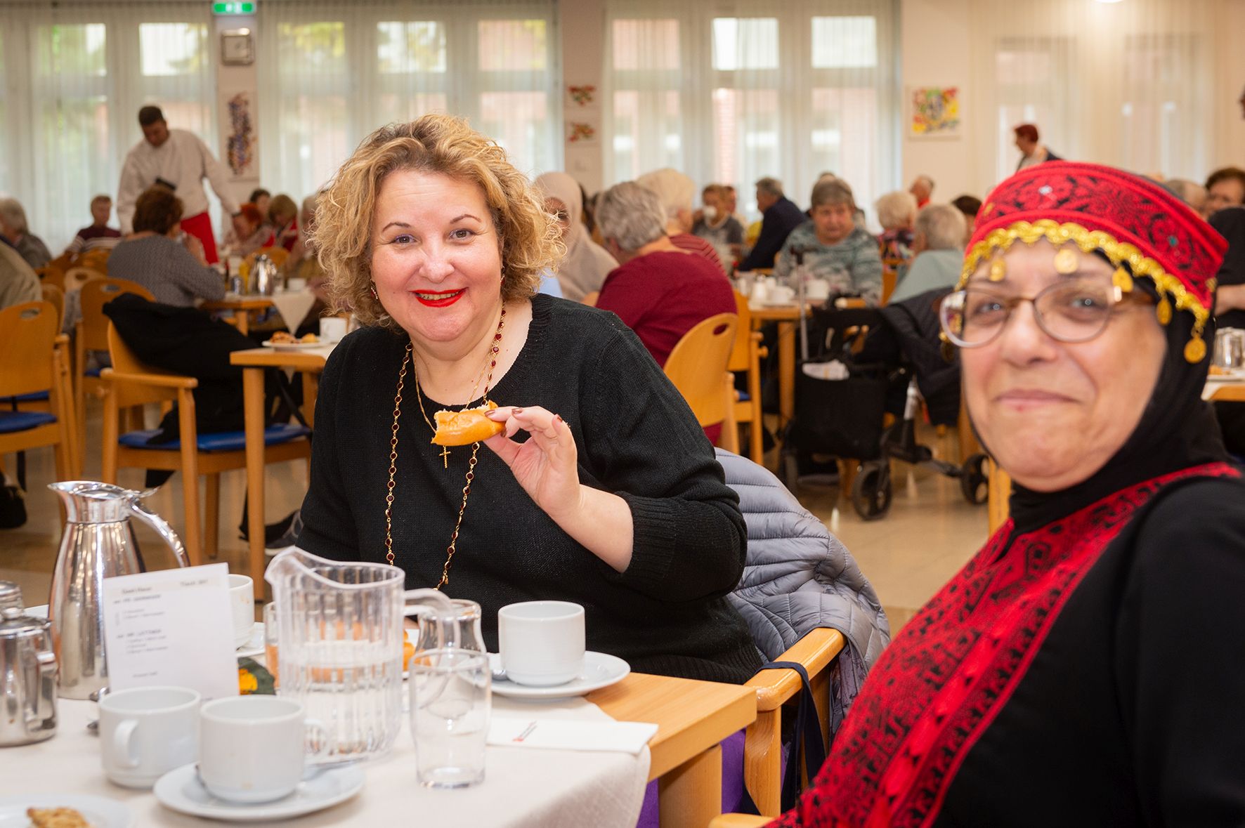 Zwei Frauen sitzen an einem Tisch bei Kaffee und Gebäck.