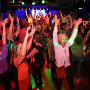 Zahlreiche Menschen, vor allem Senior*innen strecken auf der Tanzfläche der Diskothek U4 die Hände in die Höhe.
