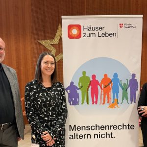 Heinz Stieb, Bereichsleiter Pflege und Betreuung Häuser zum Leben, Gudrun Bauer, Leiterin Stabsstelle Strategie und Entwicklung Häuser zum Leben, Shams Asadi, Menschenrechtsbeauftragte der Stadt Wien stehen neben einem Roll-up mit der Aufschrift "Menschenrechte altern nicht".