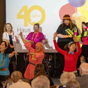 Verkleidete Personen und Tänzerinnen auf der Bühne bei der Feier "40 Jahre Haus Trazerberg"