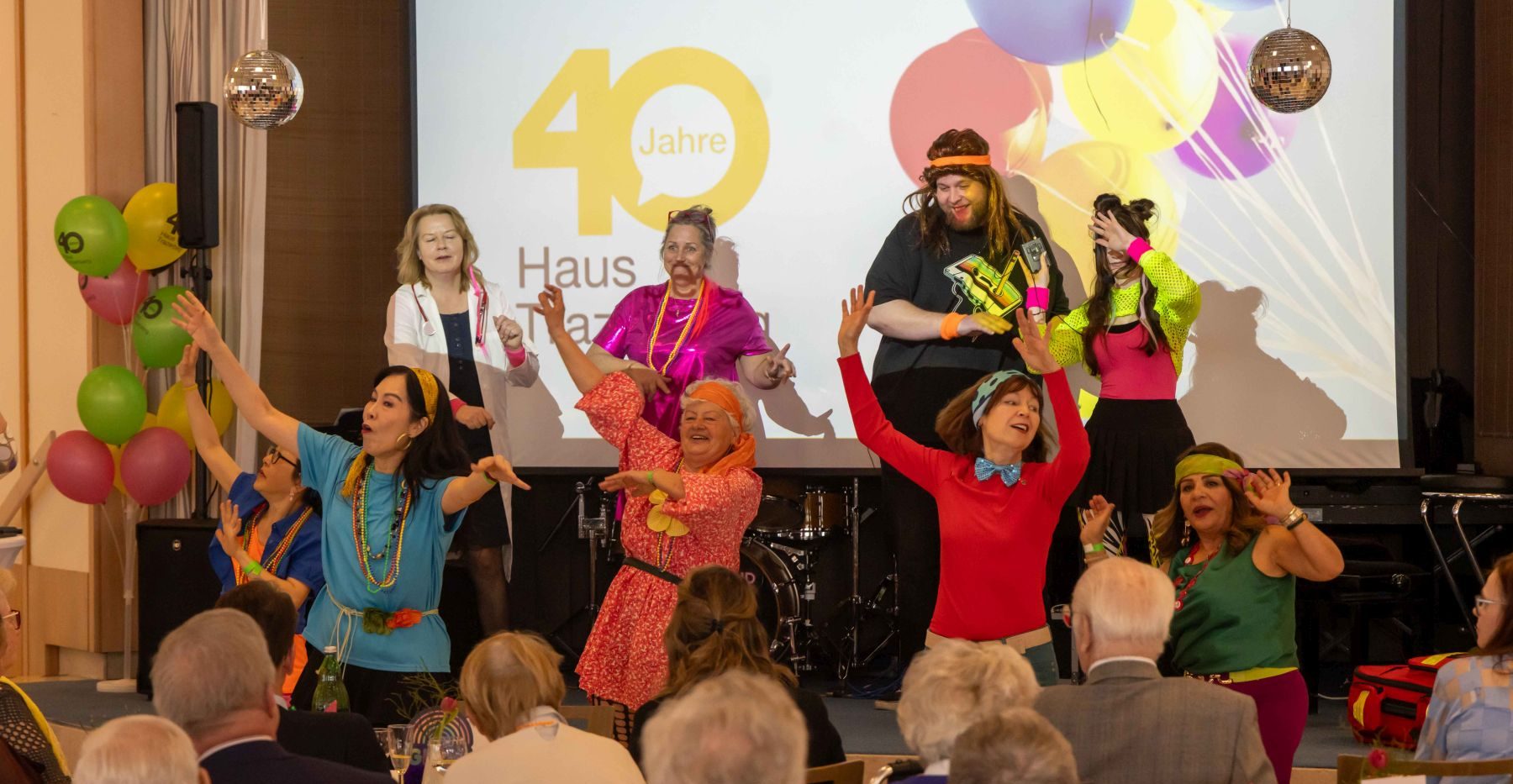 Verkleidete Personen und Tänzerinnen auf der Bühne bei der Feier "40 Jahre Haus Trazerberg"