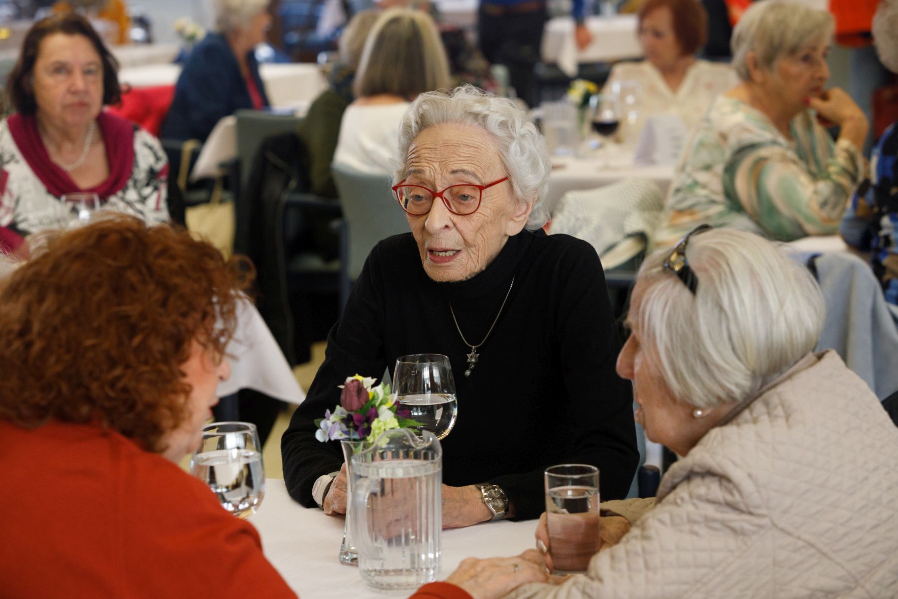 Seniorinnen sitzen an einem Tisch während der Preisverleihung und unterhalten sich.