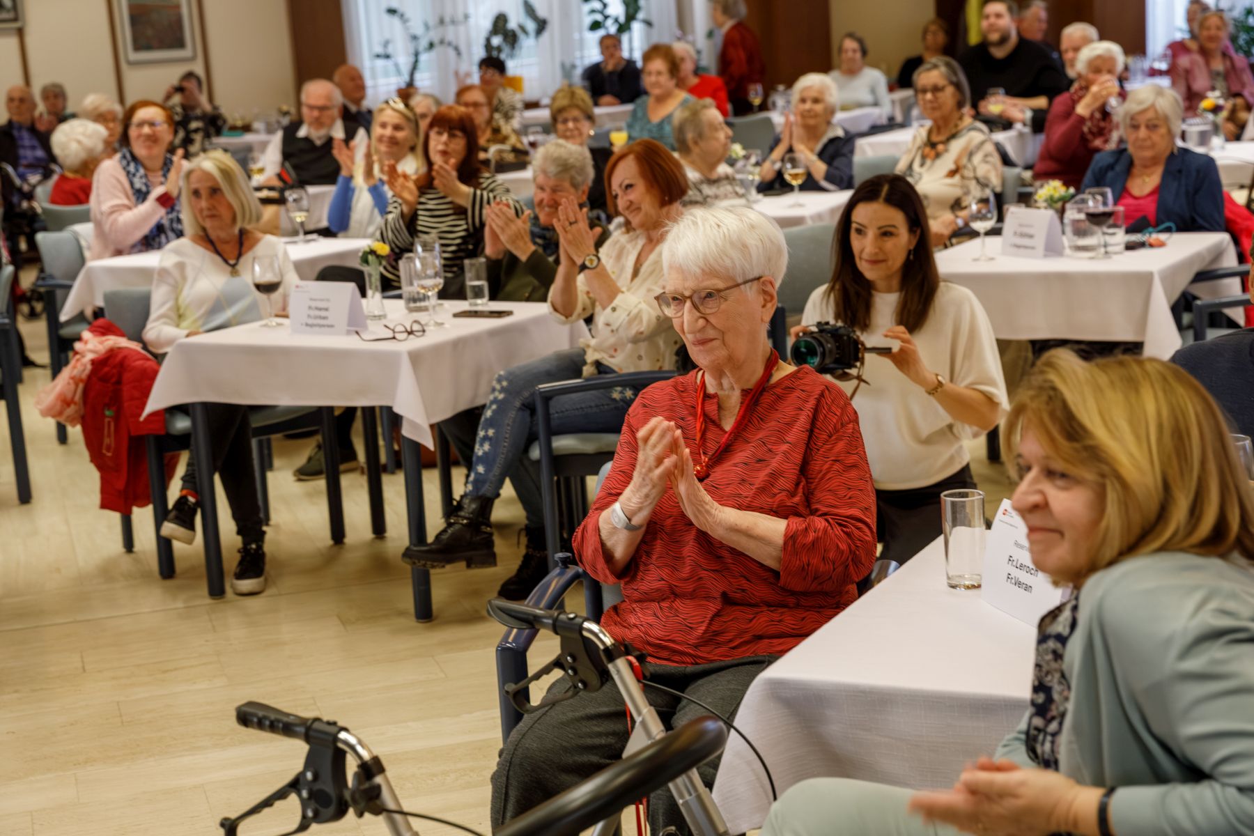 Gäste der Preisverleihung des Literatur-Contests im Haus Wieden sitzen an Tischen und applaudieren.