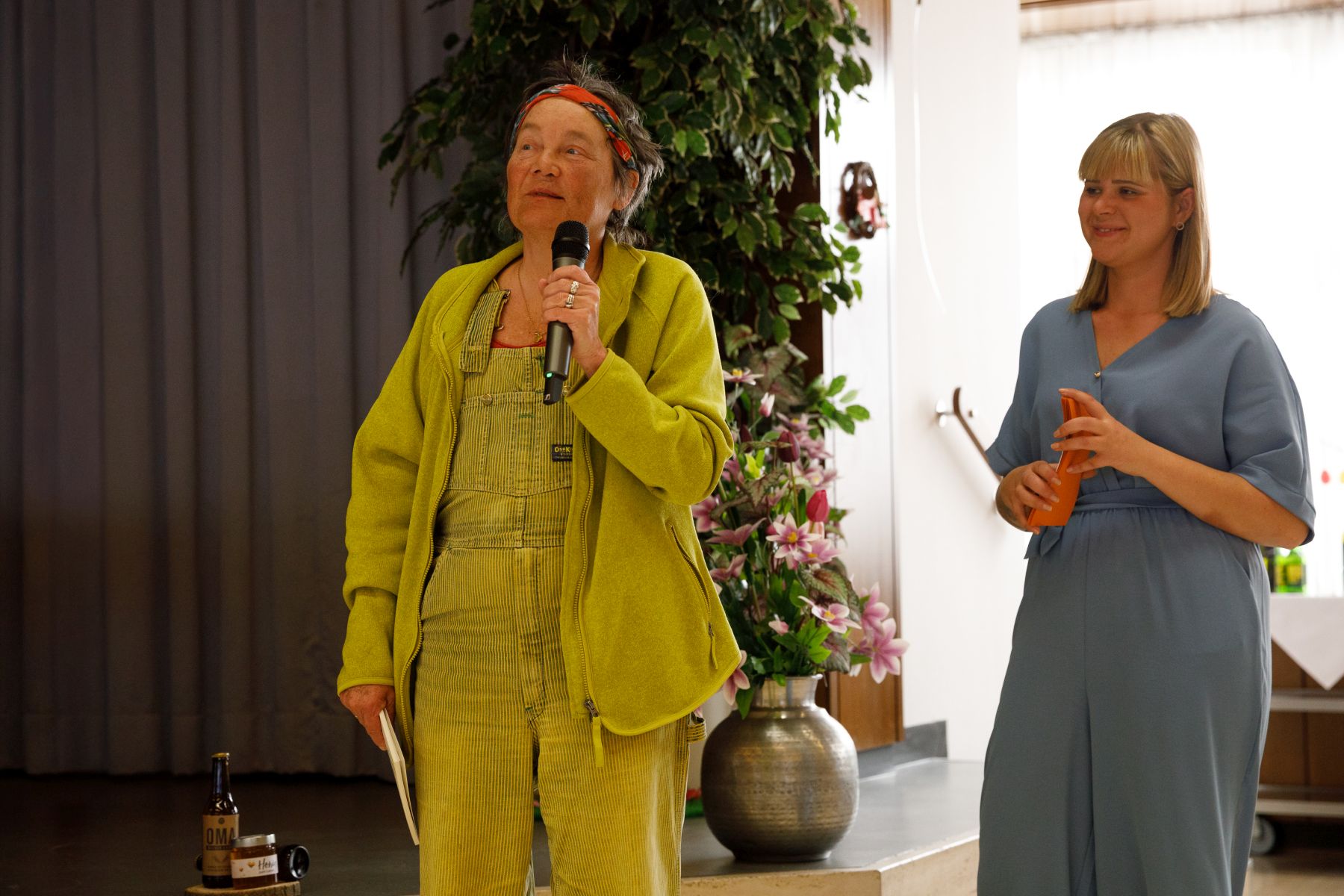 Jurysprecherin Ilse Kilic mit einem Mikrofon, daneben Moderatorin Anja Kettner