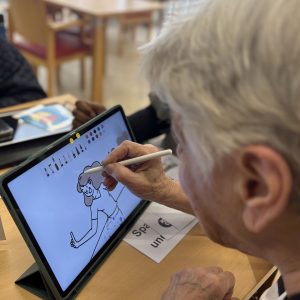Eine Seniorin zeichnet auf einem Tablet.