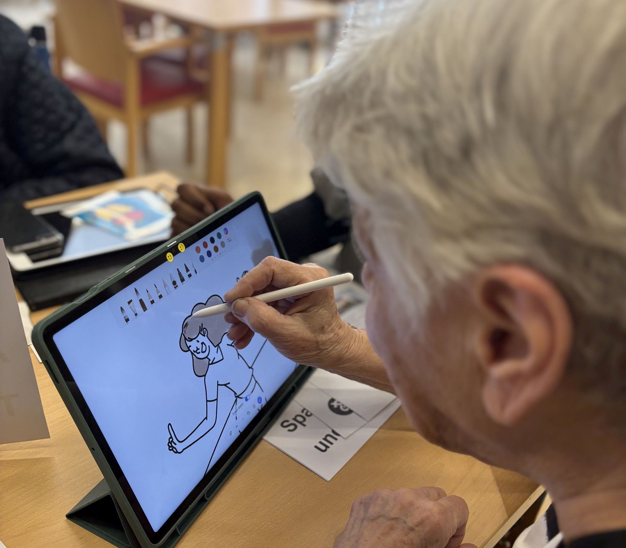 Eine Seniorin zeichnet auf einem Tablet.
