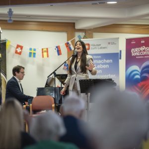 Sängerin Monika Ballwein und ein Pianist singt auf der Bühne im Pensionisten-Wohnhaus Augarten.