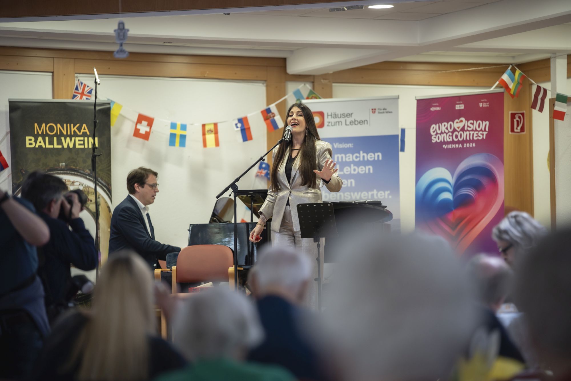Sängerin Monika Ballwein und ein Pianist singt auf der Bühne im Pensionisten-Wohnhaus Augarten.