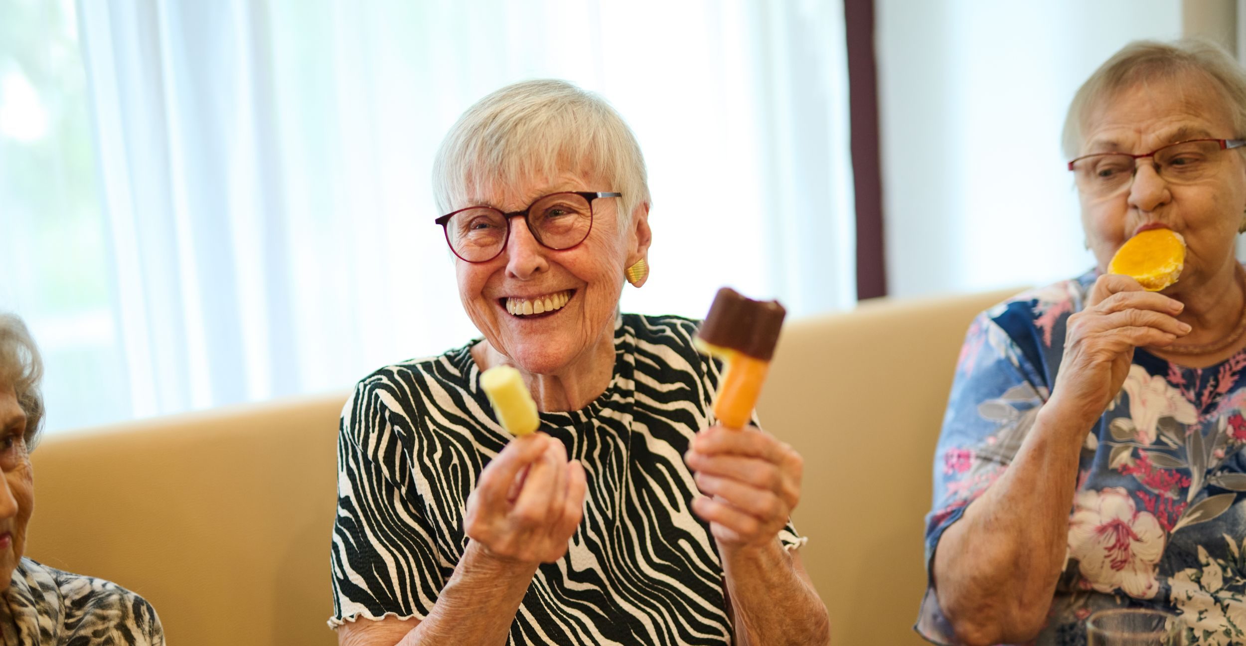 Zwei Seniorinnen lutschen Eis am Stiel.