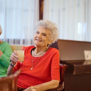 Zwei Seniorinnen halt ein Glas mit einem Getränk in der Hand.