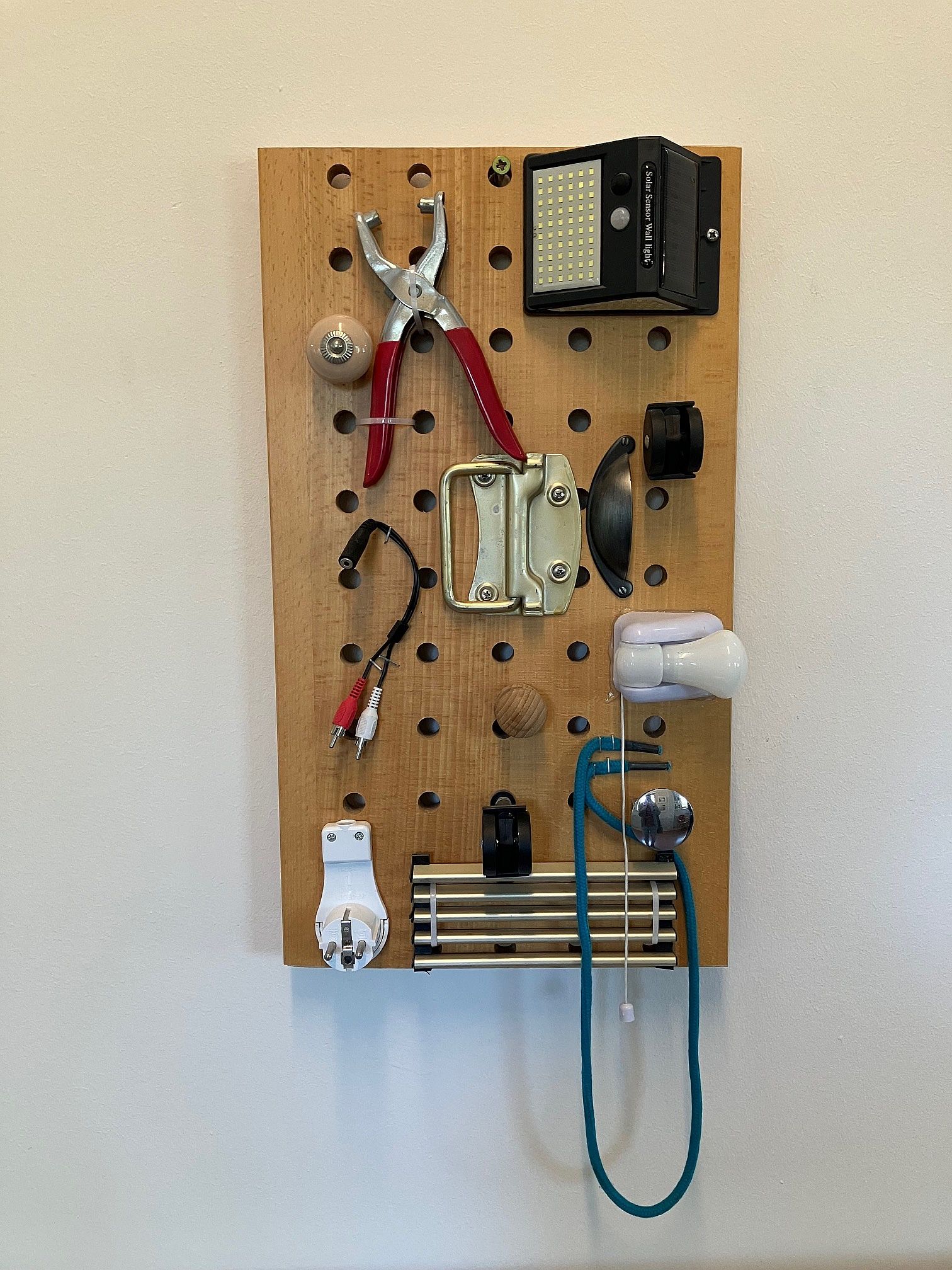 wand tagfamiilie Eine Holztafel mit verschiedenen befestigten Gegenständen (Zange, Stecker, Kabel, Lampe) für Bewohner*innen mit Demenz.