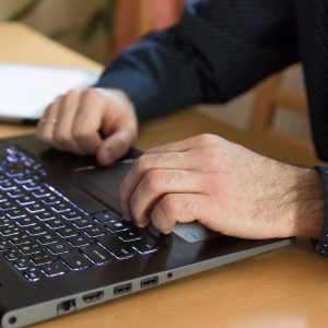 Zwei männliche Hände an einer Laptop-Tastatur.