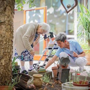 Eine Seniorin und eine Pflegerin bei der Gartenarbeit im Haus Rosenberg.